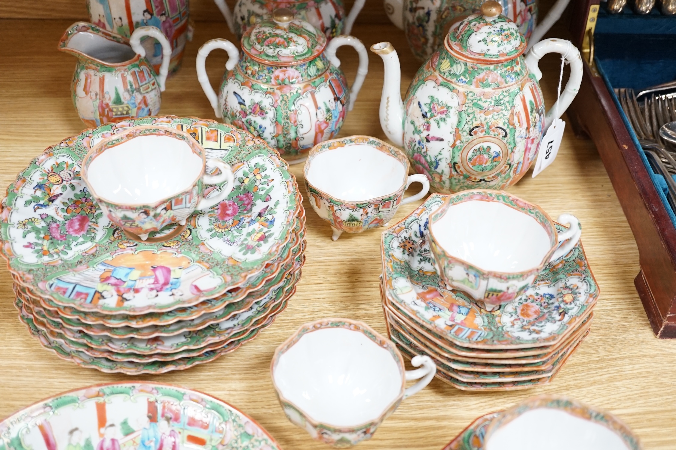 A Chinese famille rose six place setting tea service, including a large tea pot and cover, a smaller water pot and cover, two sugar bowls with covers, a large milk jug (handle broken) a small cream jug and a cake plate,(